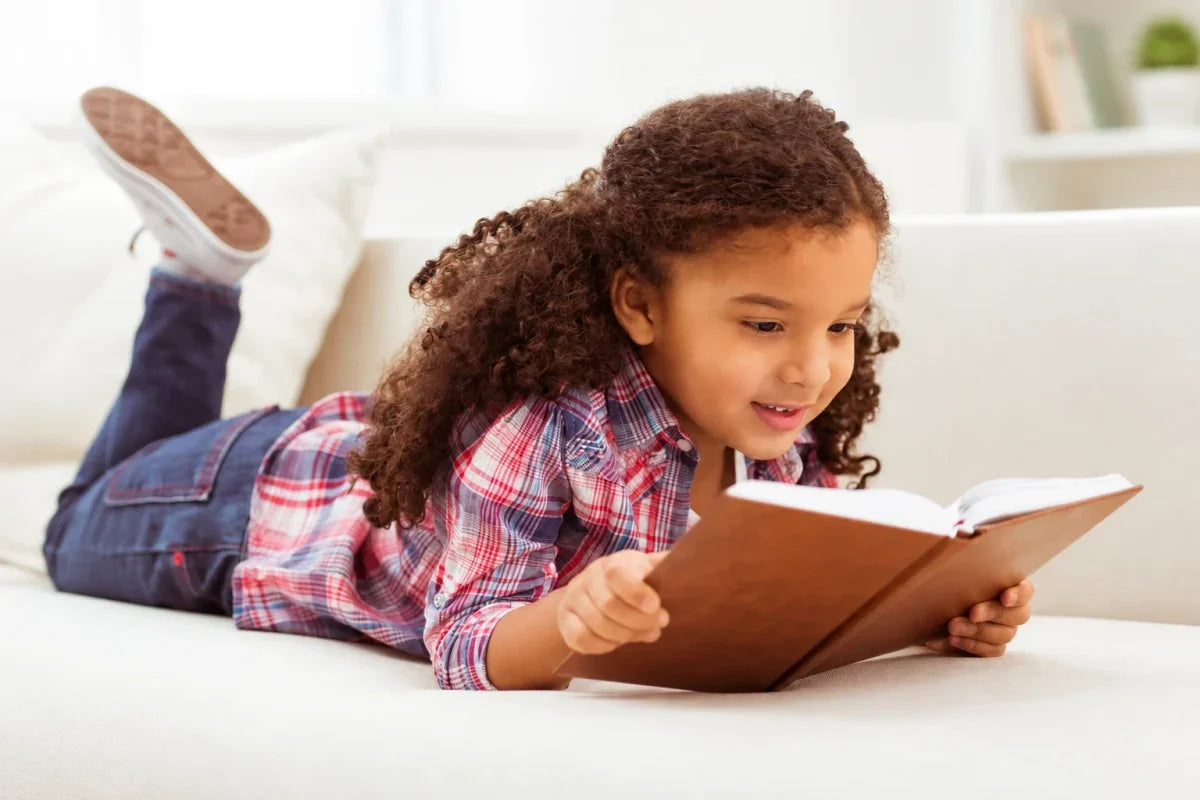Girl reading a book while lying on a bed