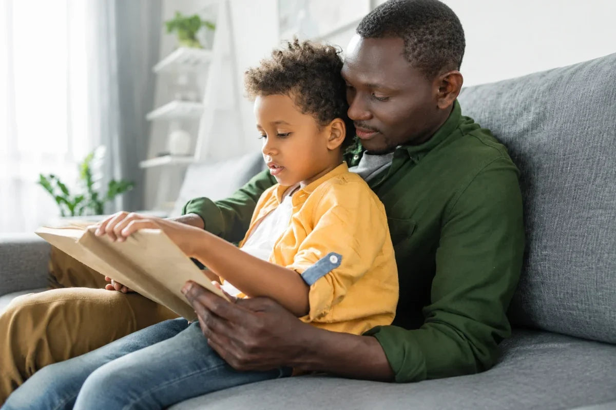 Father reading a book with his young son on a couch