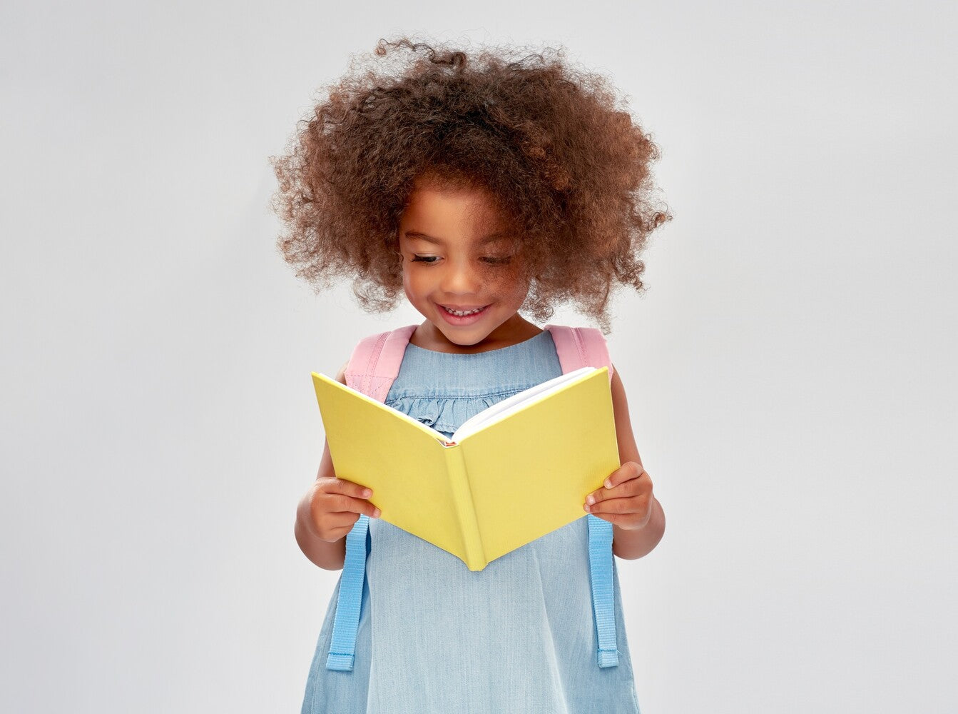 a young girl happily reading and answering the question, is reading good for your brain
