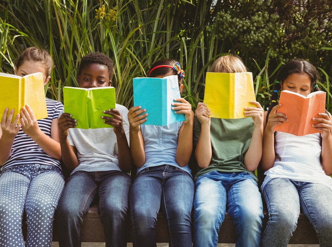 children reading together in the park demonstrating the answer to why is reading important for kids