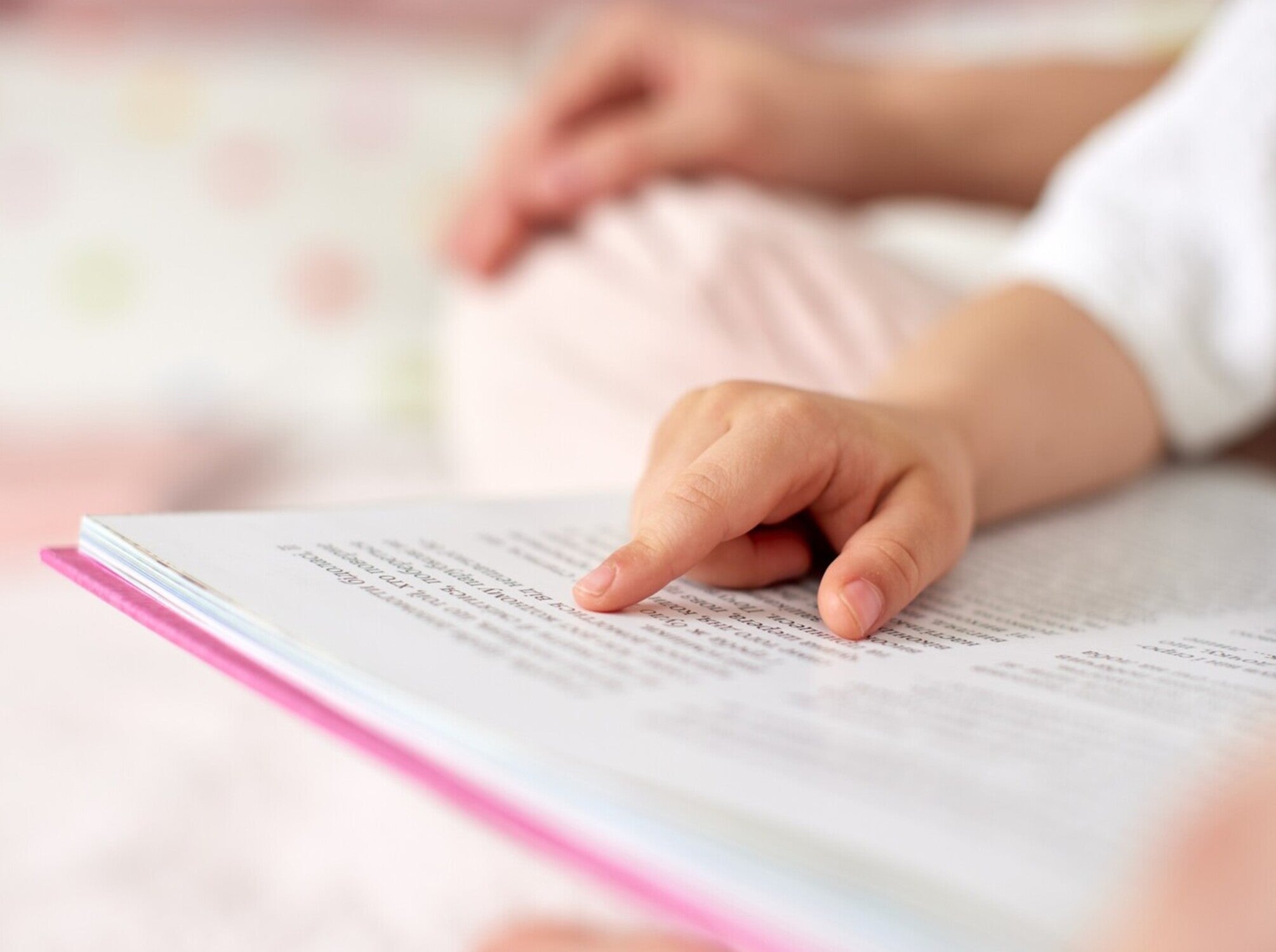 closeup of a child pointing at words in a storybook, showing how to promote literacy in early childhood