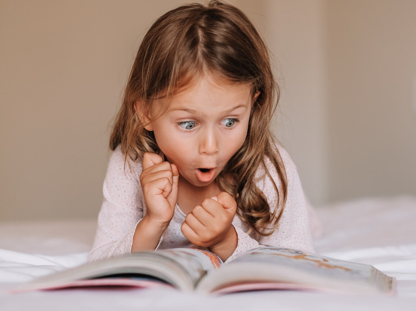 little girl enjoying her book at home after her parents learned how to get kids excited about reading