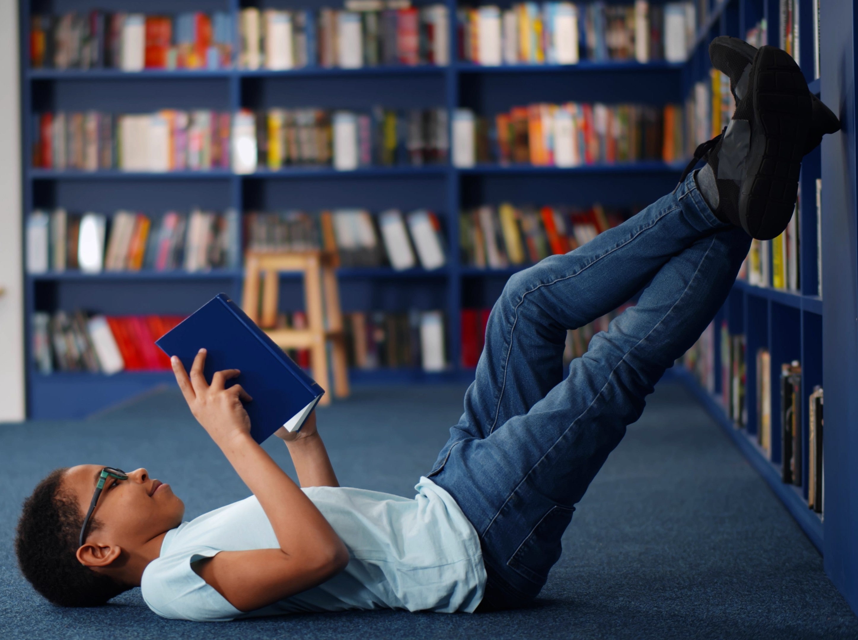 young boy having fun reading in a library after his parents learned how to encourage reading in kids