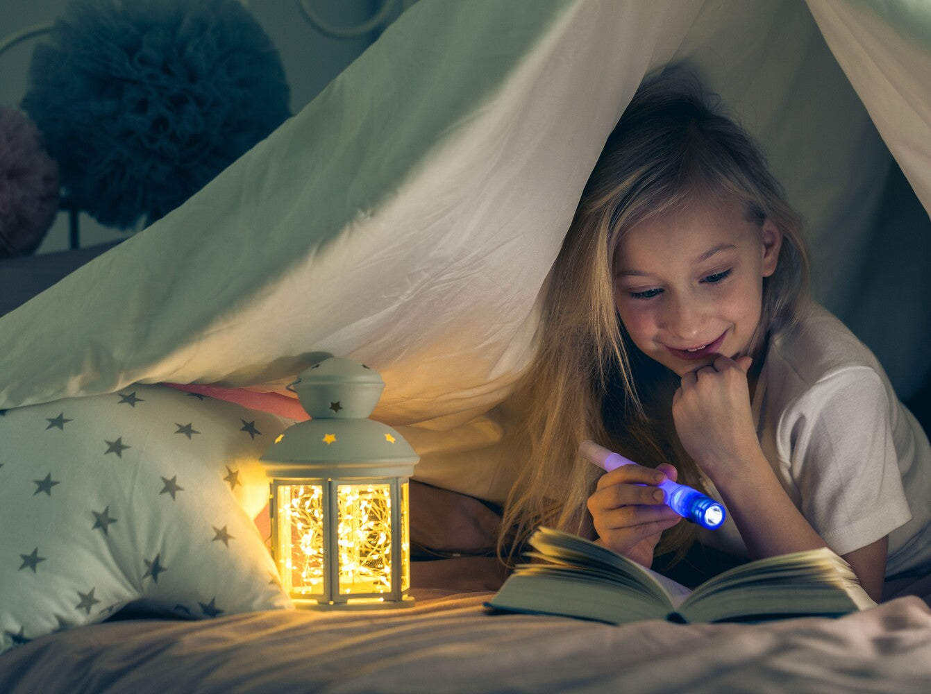 young girl enjoying a book in a pillow fort, showing how to make reading fun for kids
