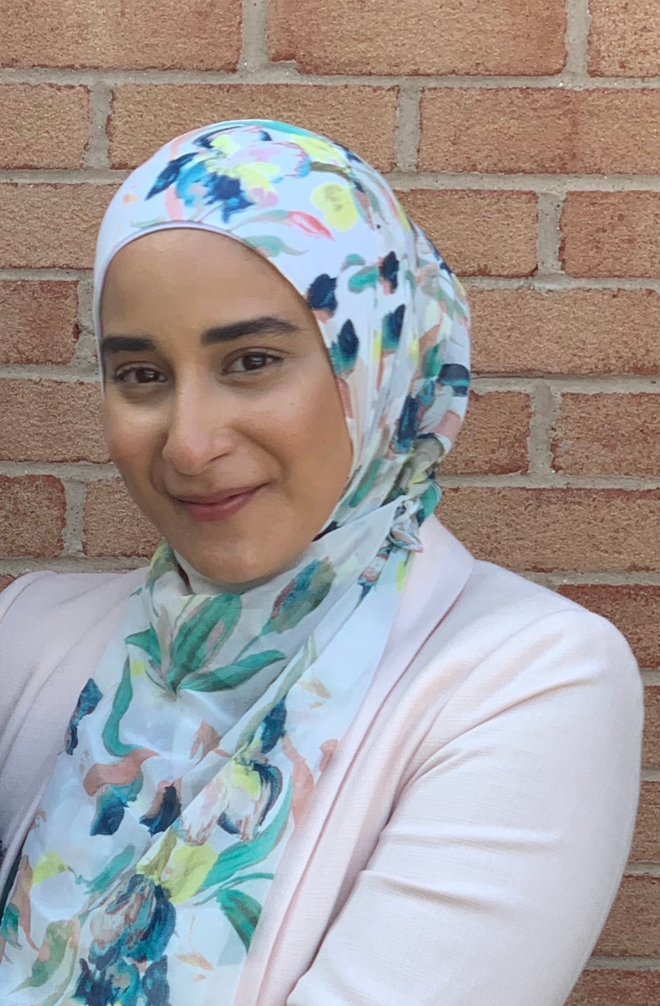 Ahlam headshot, smiling with floral hijab.