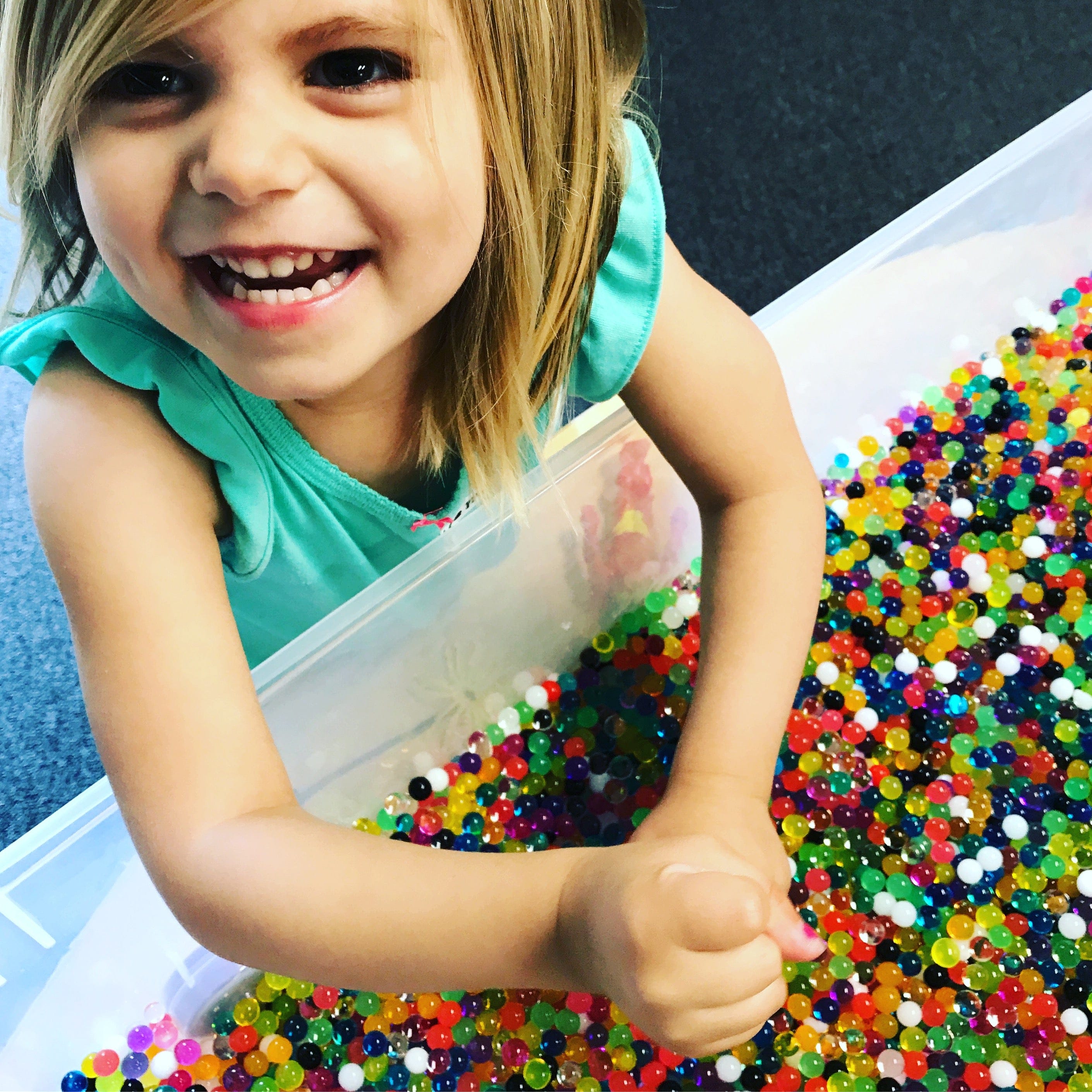Smiling girl playing with colorful water beads