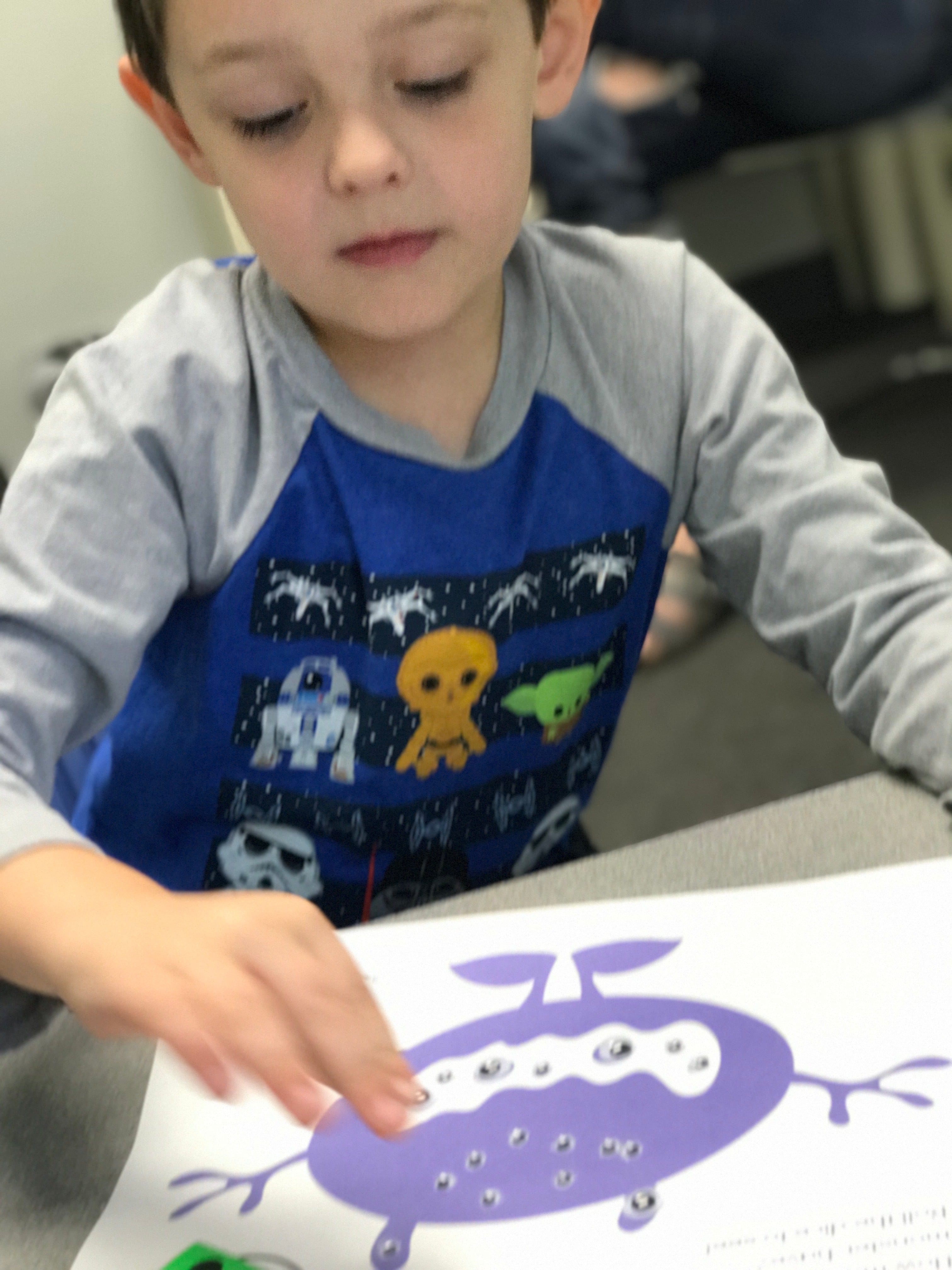 Boy looking at a book with a purple illustration.
