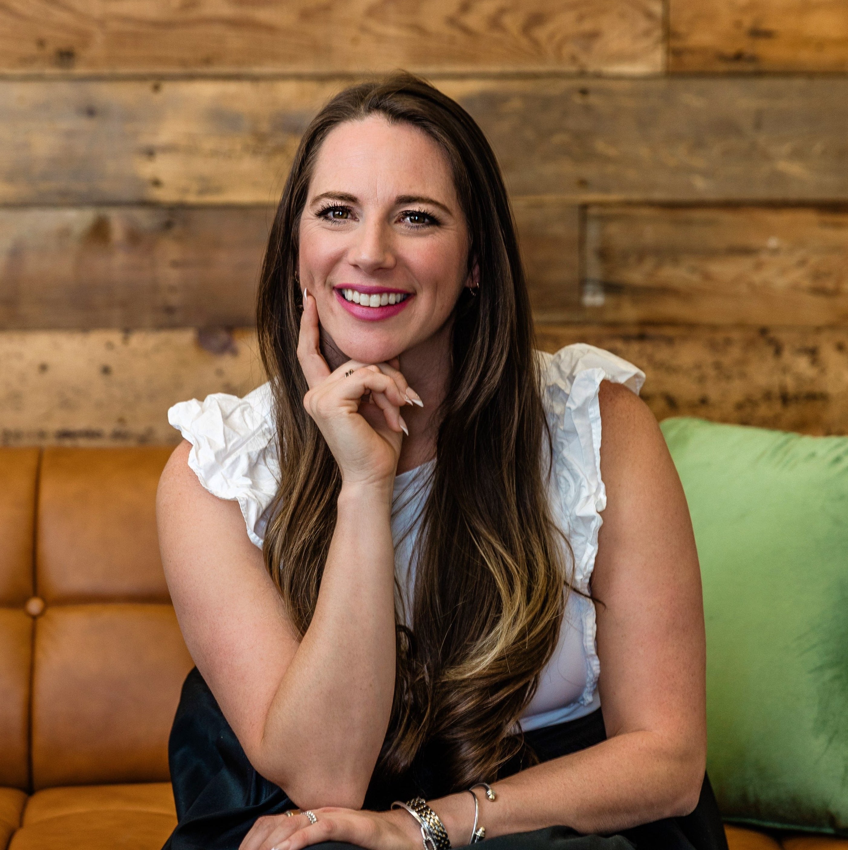 Woman sitting on a brown leather couch with a wooden wall background