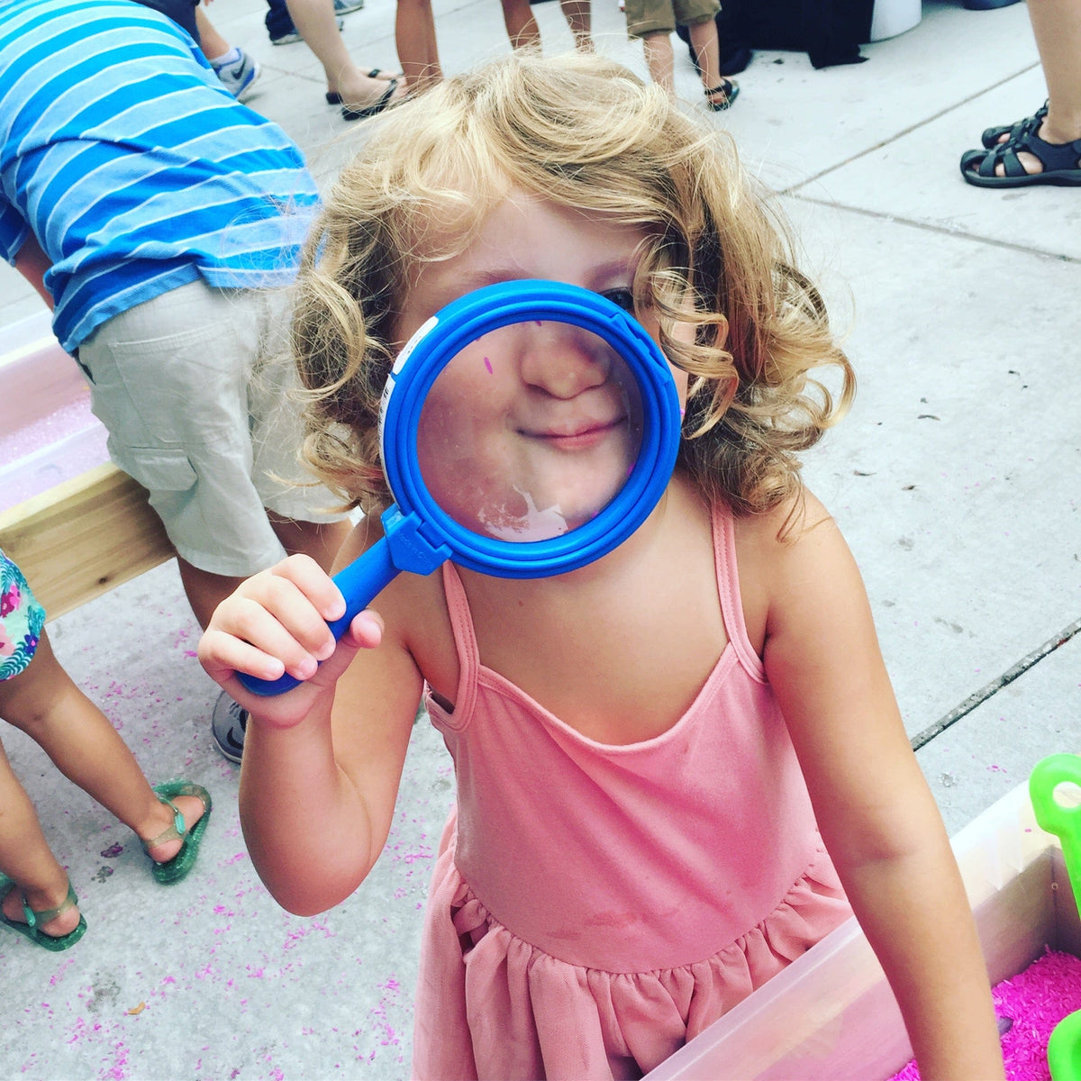 Girl looks through magnifying glass.