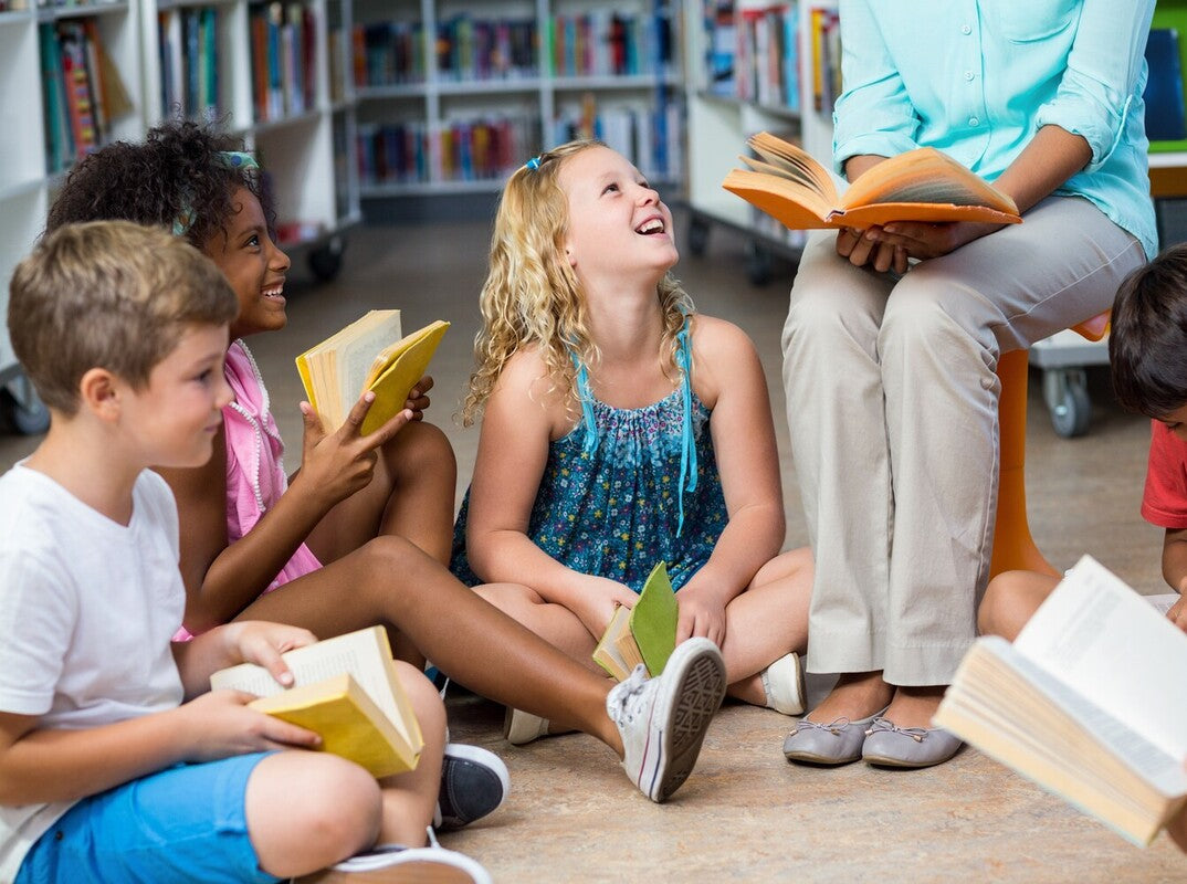 children enjoying the fun benefits of reading books together by reading in class