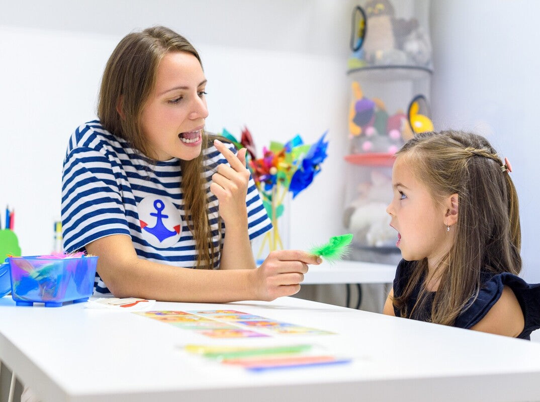 speech therapist showing how to help a child with speech apraxia by using flash cards alongside modeling