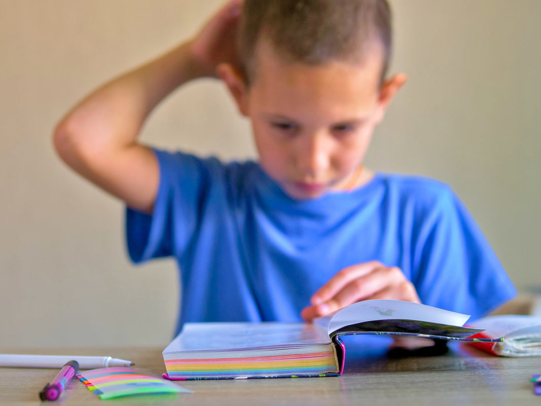 young boy struggling to read a book before learning how to help a child struggling with reading