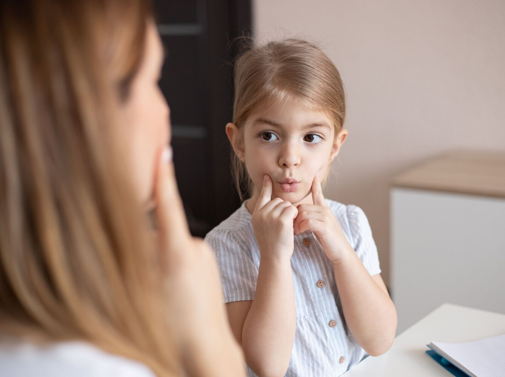young girl working with a speech therapist to detect early signs of childhood apraxia of speech