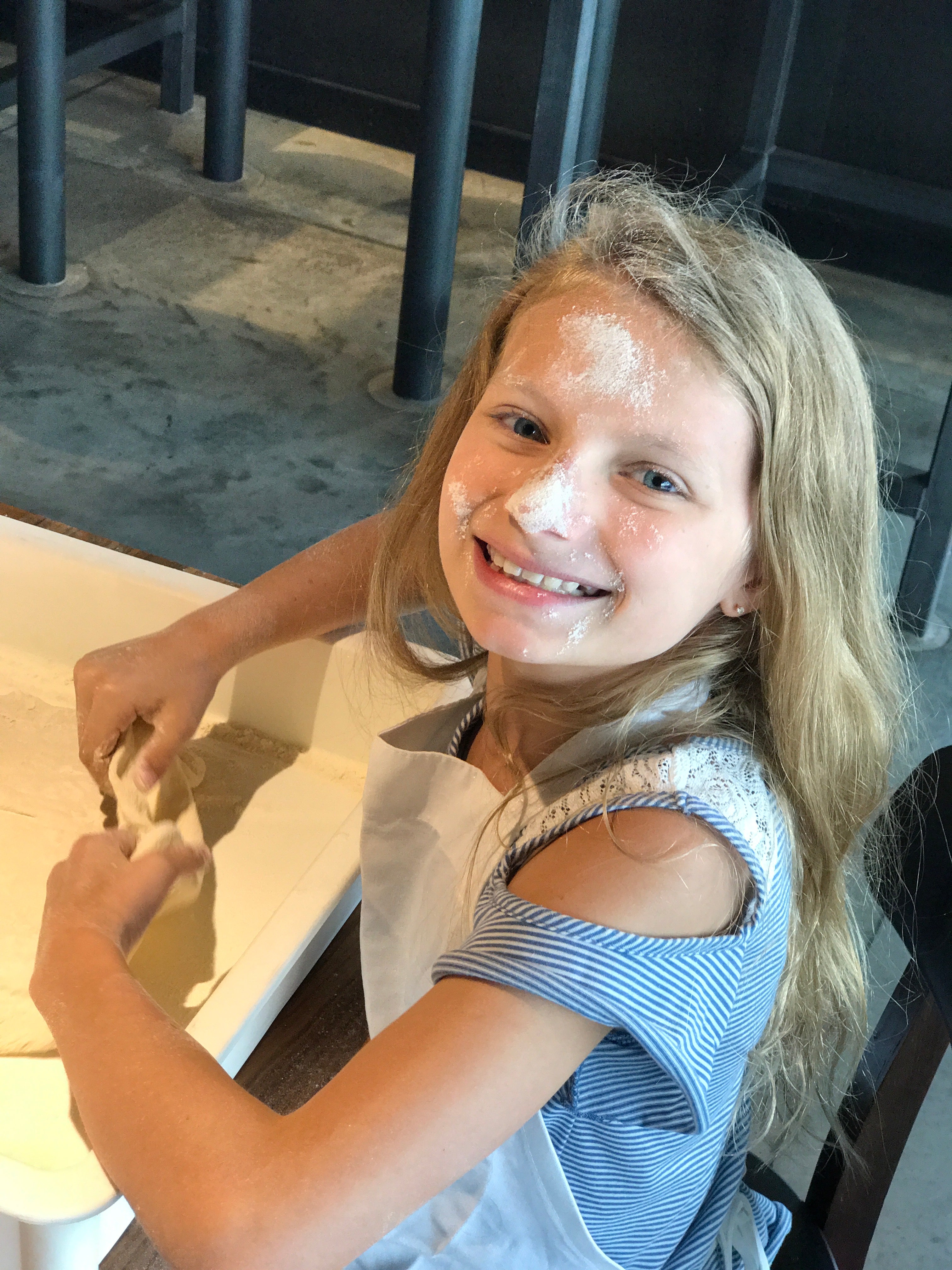 Girl making pizza, flour on face