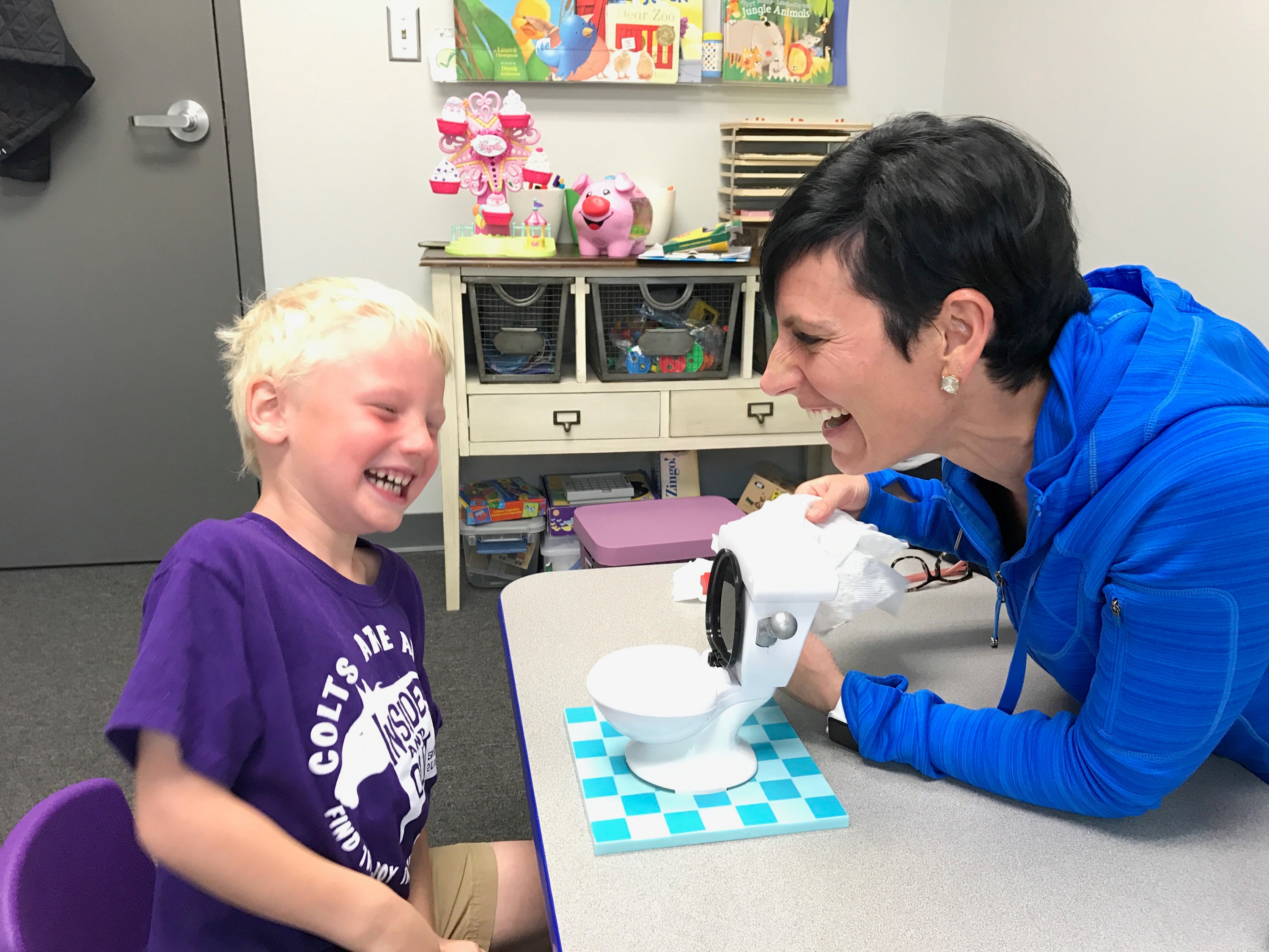 Jennie Bjorem, SLP and boy laughing at a toy toilet.