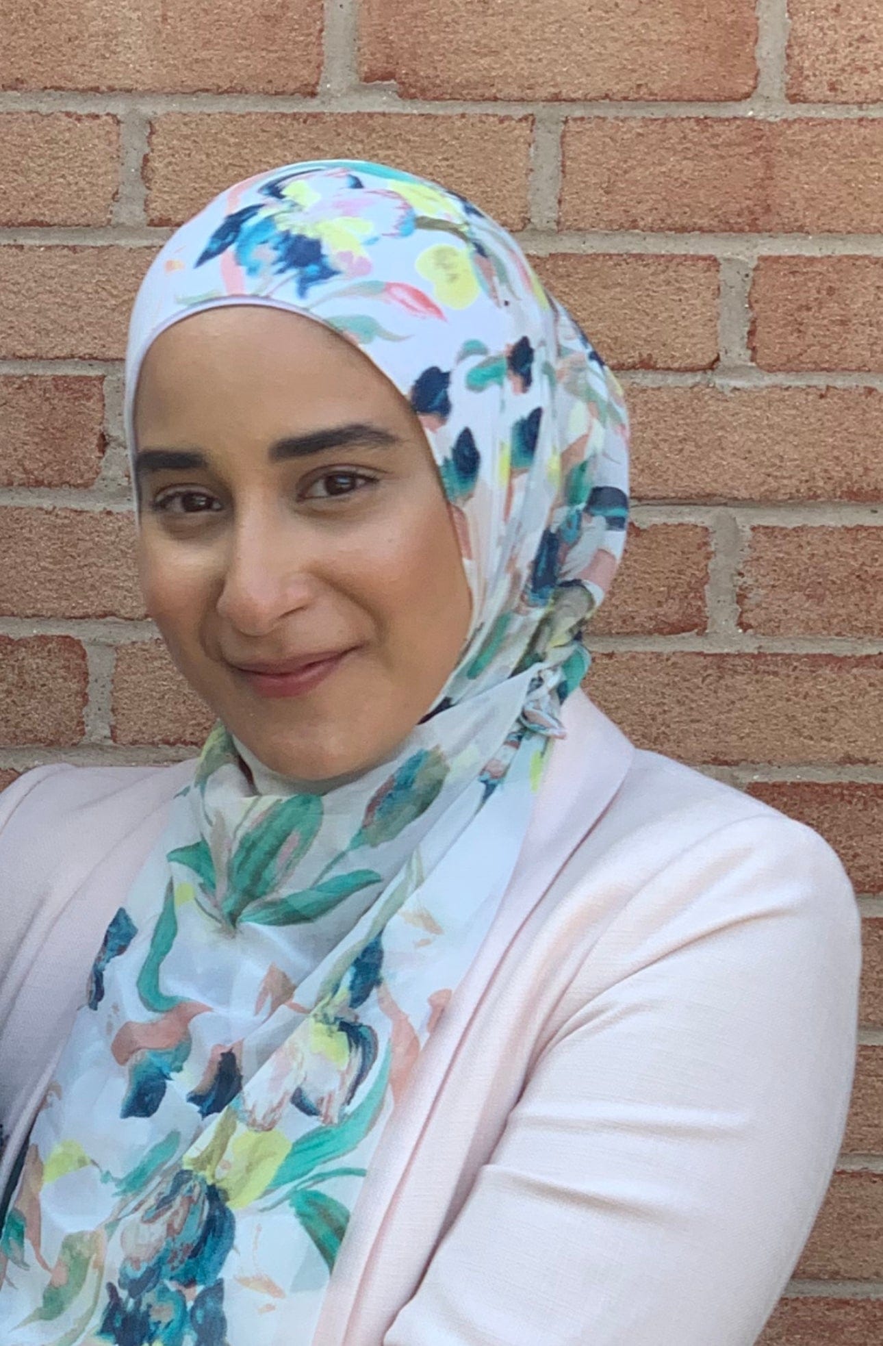 Ahlam headshot, smiling with floral hijab.