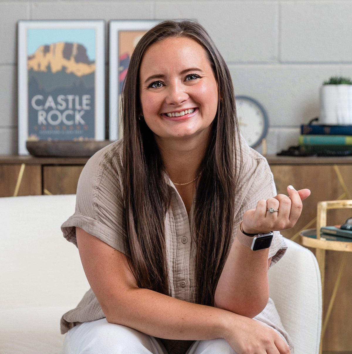 Kallie sitting on a white chair in a modern living room