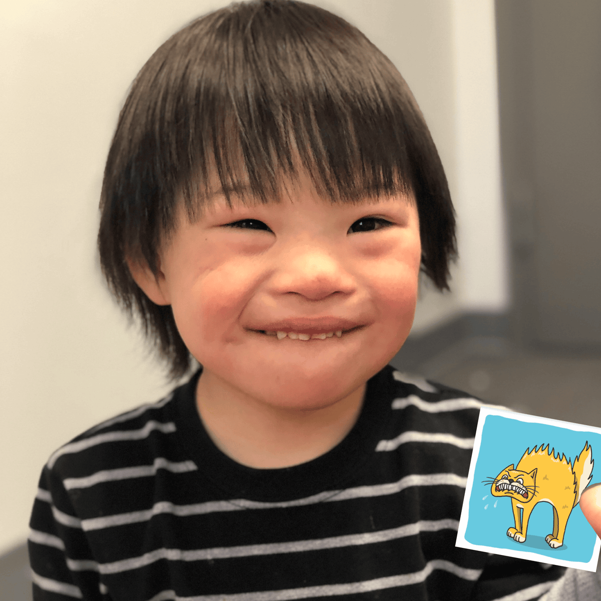 Smiling child with short dark hair and a cartoon cat image.