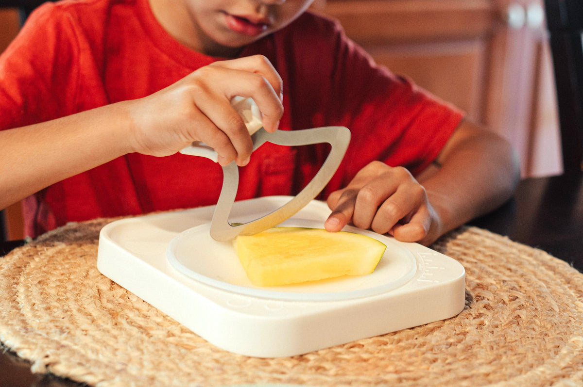 Child cutting food with the Totchop rocker knife